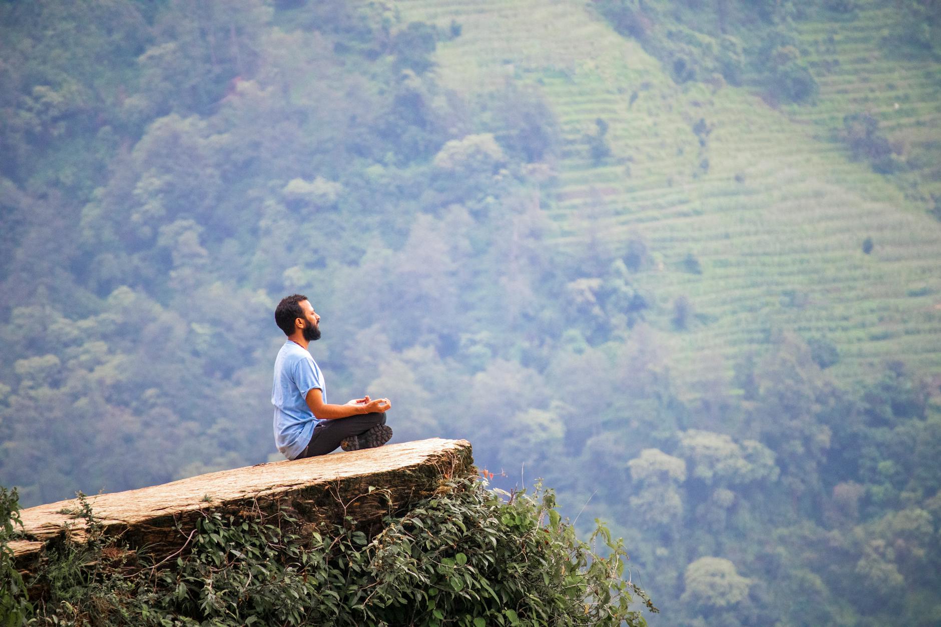 A serene landscape showing a person meditating in nature