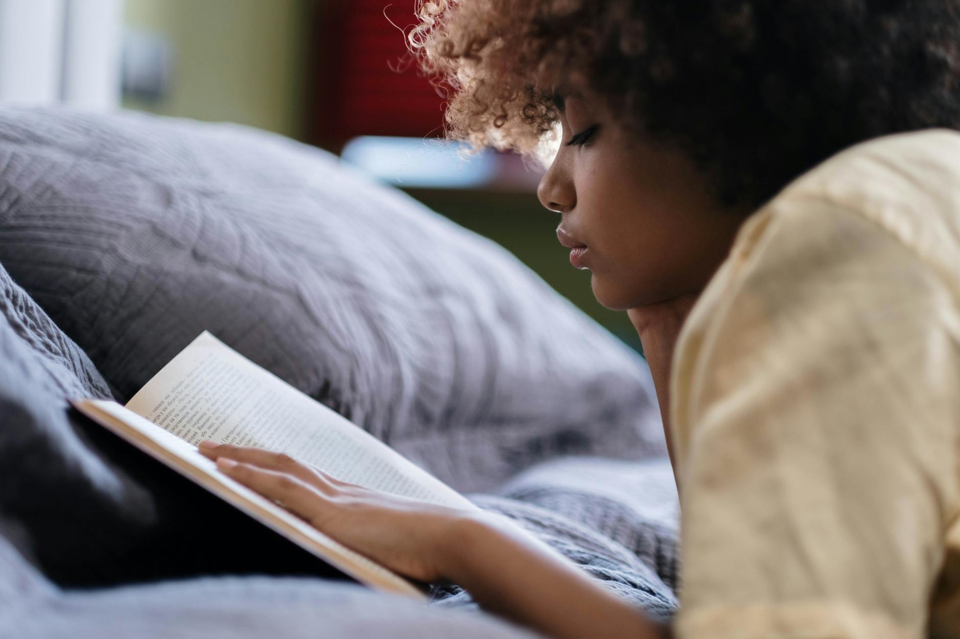 person reading a book in bed before sleep