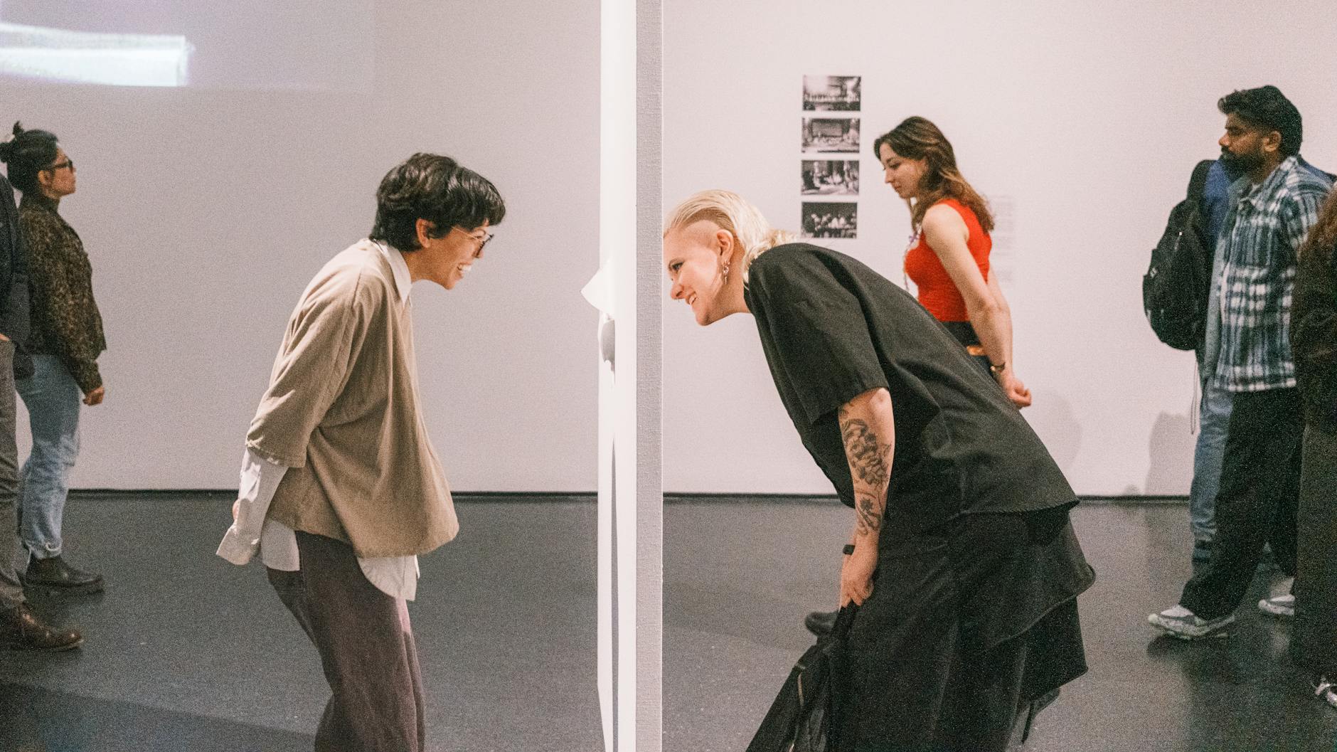 Elegantly dressed attendees at an art fair engaging in conversation amidst modern art installations.