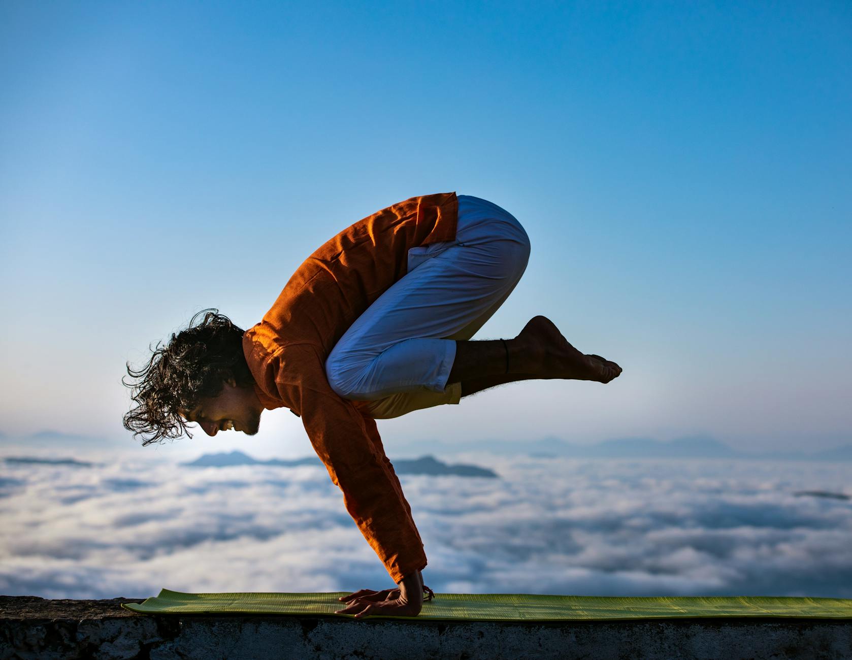individual practicing yoga outdoors at sunrise